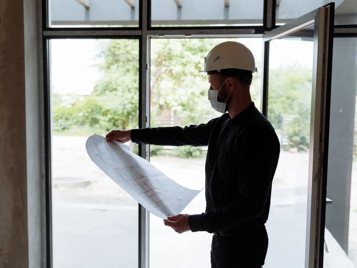 Técnico con casco revisando planos en una obra interior